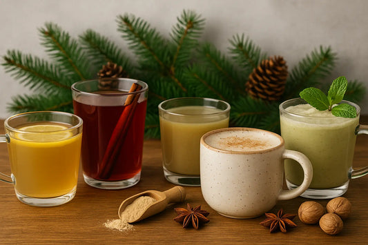 Five holiday-themed functional drinks made with kava displayed in glass and ceramic cups on a wooden table, surrounded by pine branches, cinnamon sticks, star anise, mint leaves, walnuts, and kava powder — showcasing cozy winter beverage inspiration.