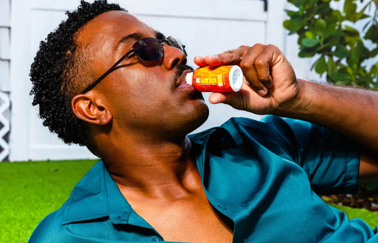 Man relaxing outdoors while drinking a Mitra9 botanical shot, showcasing a functional kava drink alternative in a sunny backyard setting.