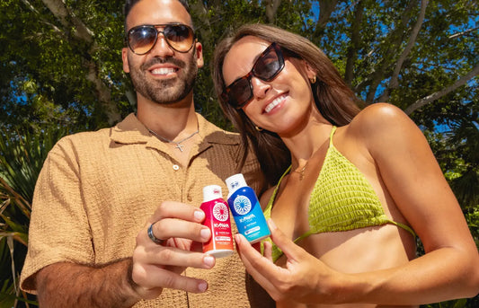 Couple enjoying Mitra9 functional drink shots outdoors in sunny tropical setting, showcasing botanical kava beverage as an alcohol alternative.